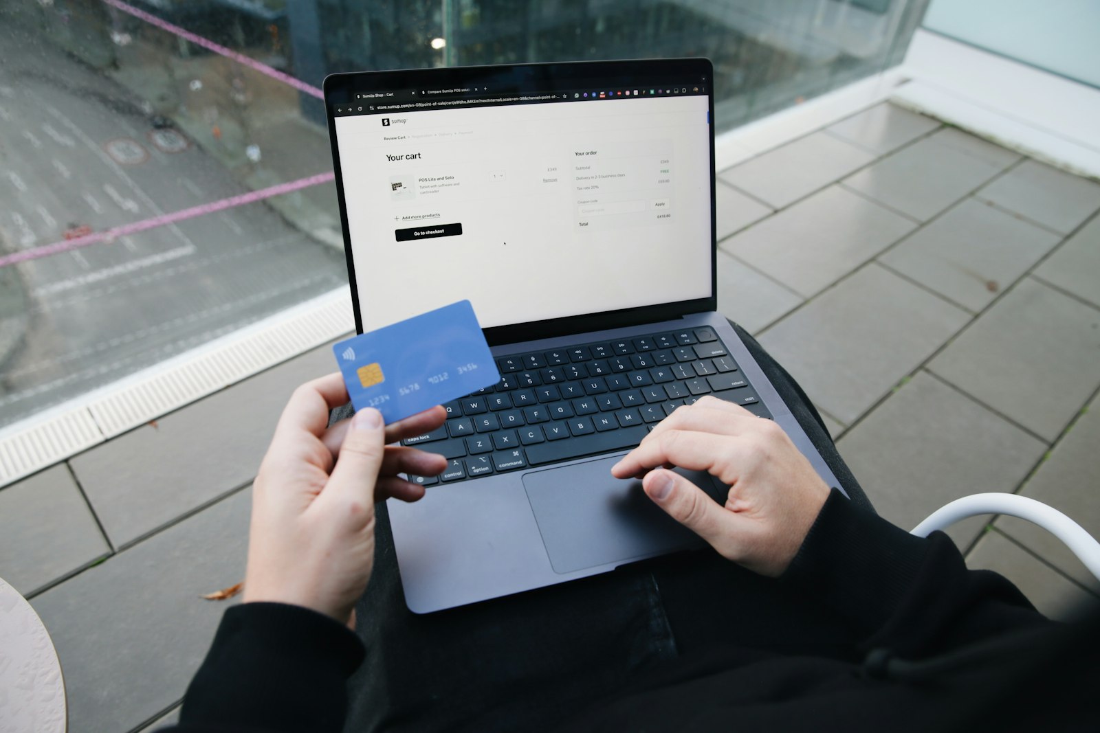 Person at a laptop holding a credit card during an online purchase