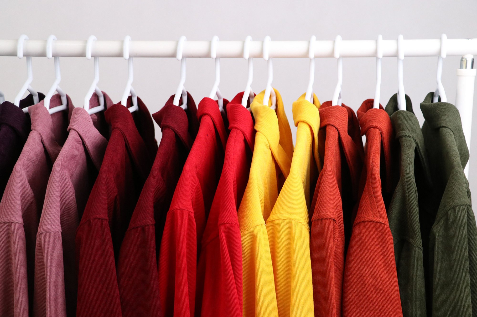 The same shirt in several colors, hanging in pairs on a white clothing rack