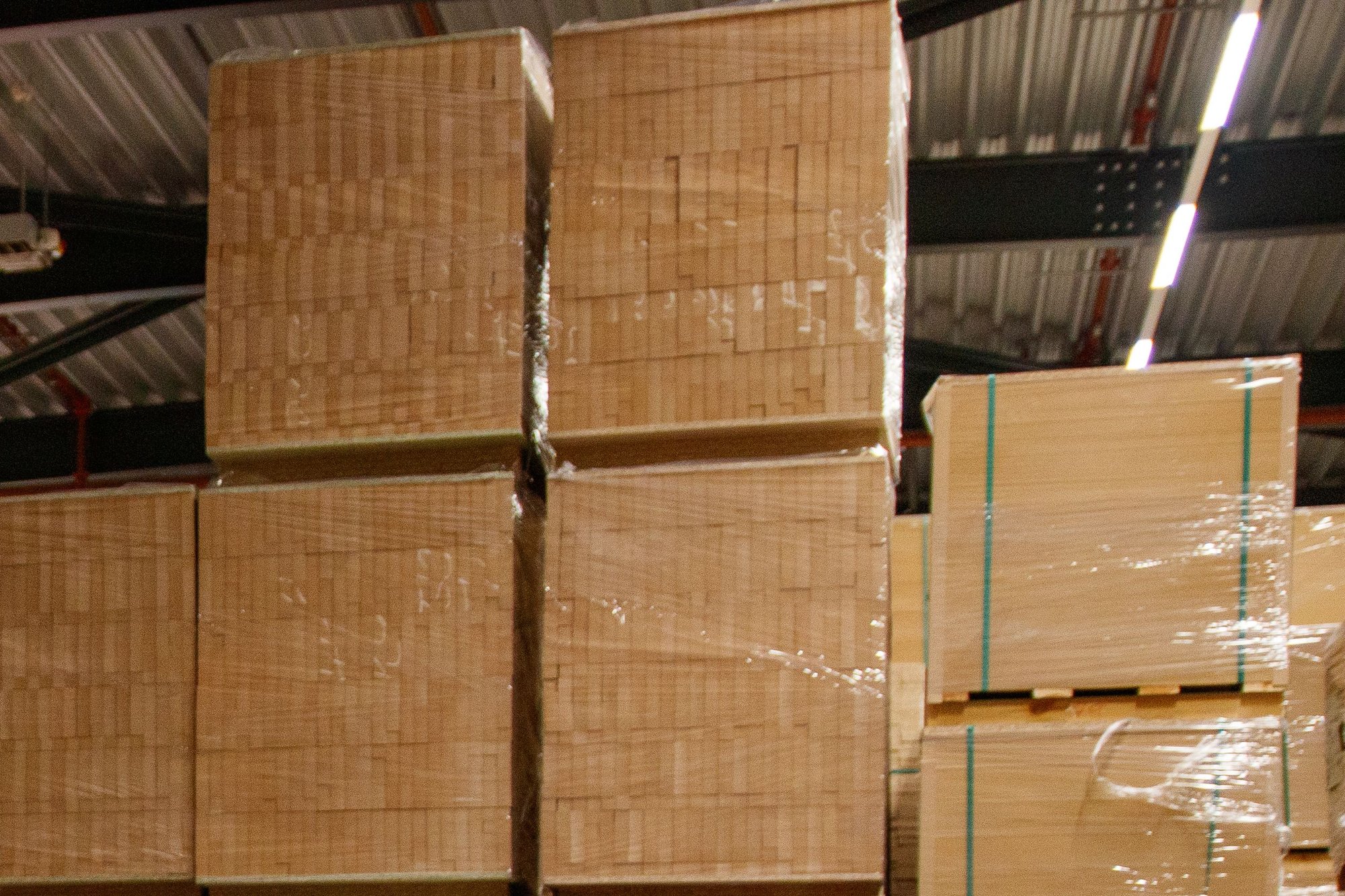 Pallet stacks of plain brown cases wrapped in plastic inside a warehouse